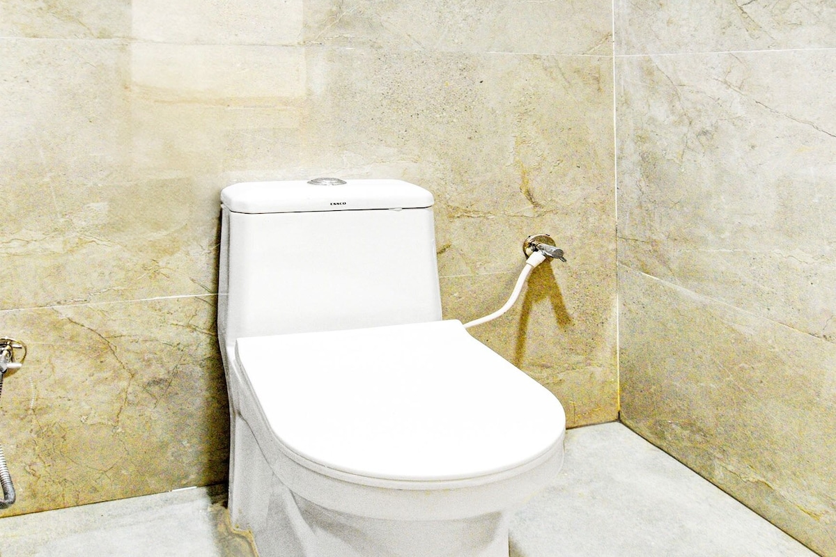 Lavabo blanc en un bany amb parets de marbre i zona de dutxa.