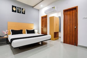 A hotel room with a bed, bedside table, lamp, and a wardrobe. - Townhouse Shamshabad Near Airport (Hyderabad)