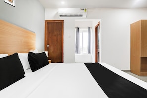 A hotel room with a bed, a wooden headboard, a wardrobe, and a window with curtains. - Townhouse Shamshabad Near Airport (Hyderabad)