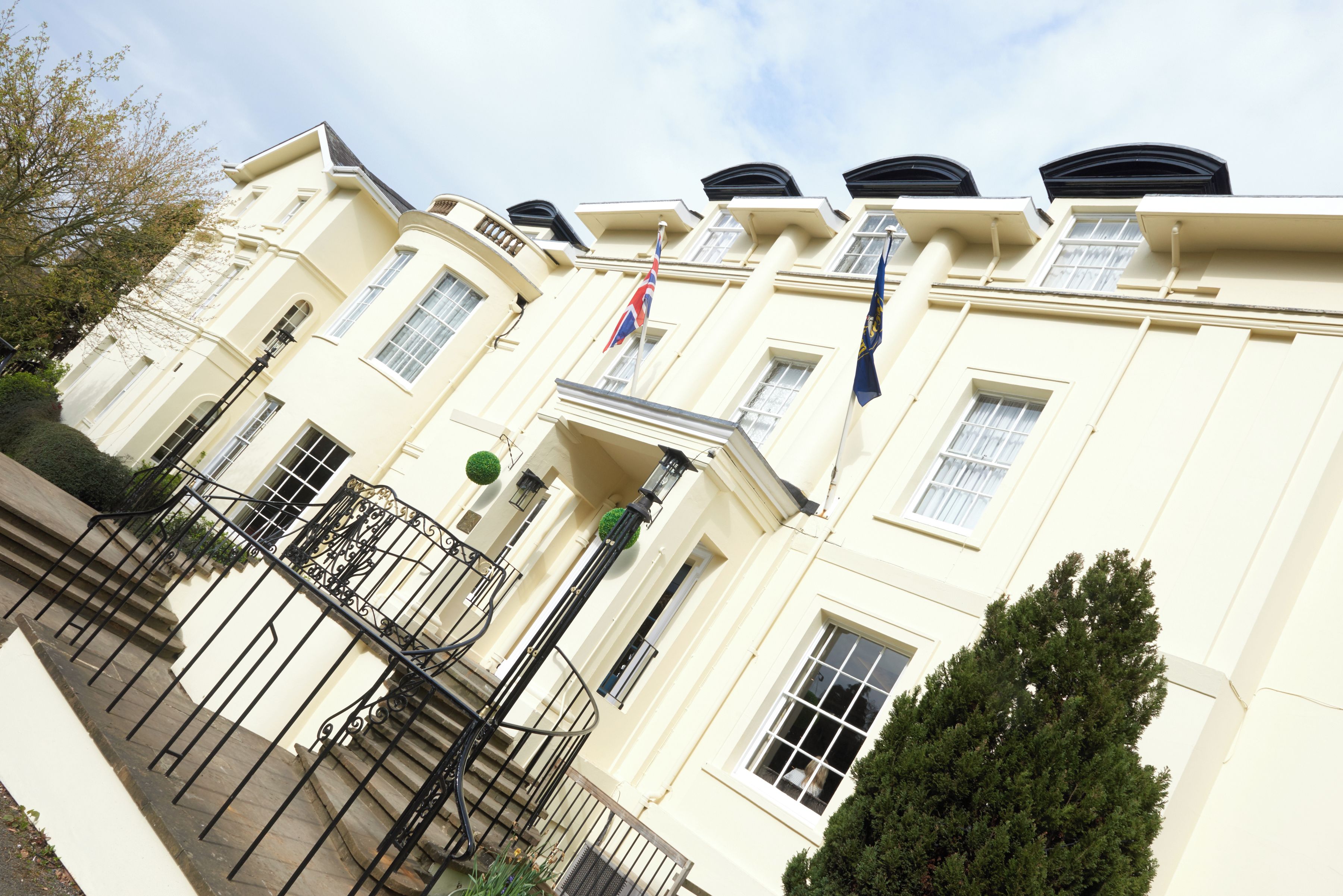 A multi-story building with a symmetrical facade, large windows, and a central entrance with a flag.