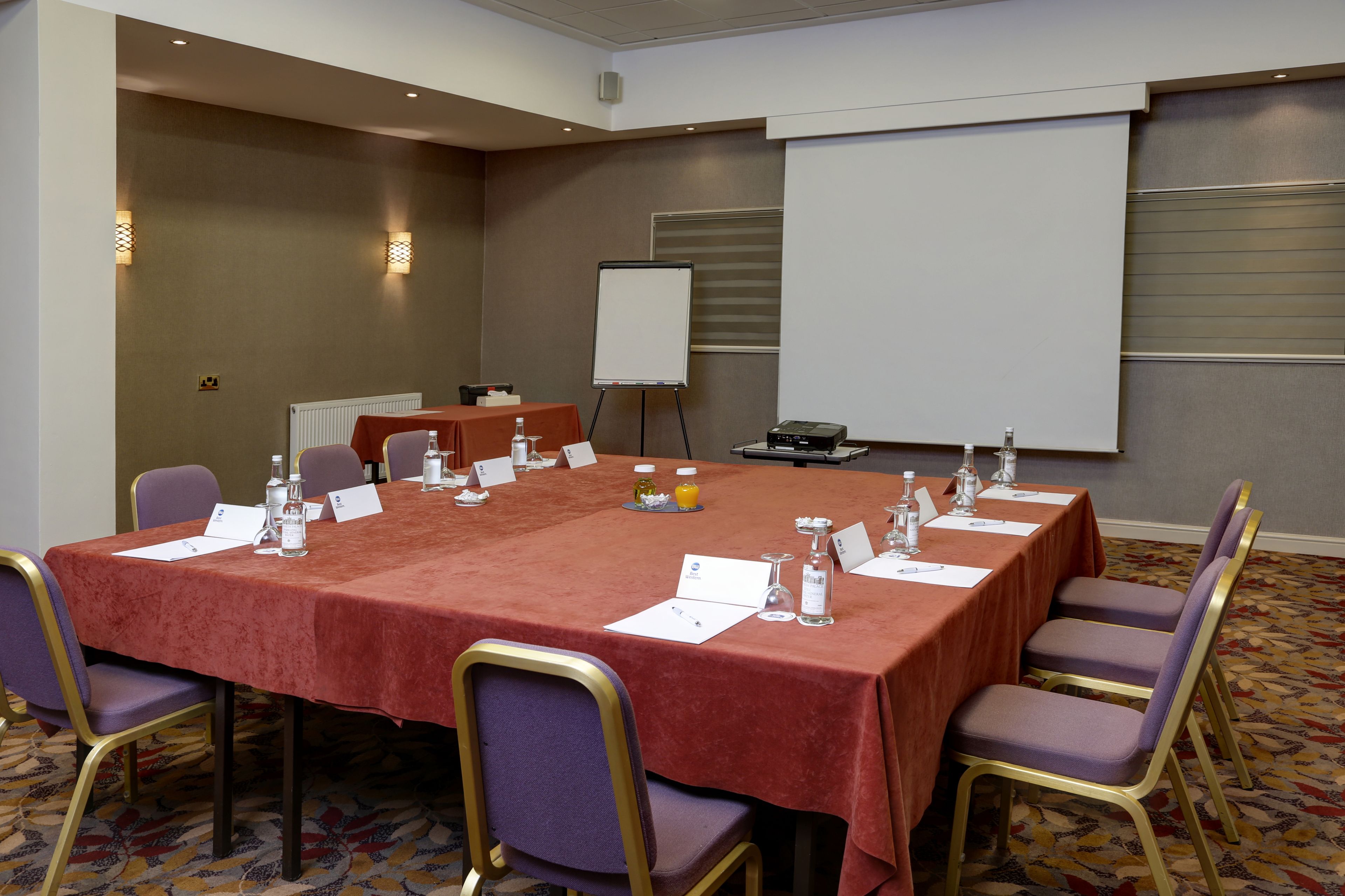 Ein Konferenzraum mit einem langen Tisch, Stühlen, einem Projektor und einer Tafel.