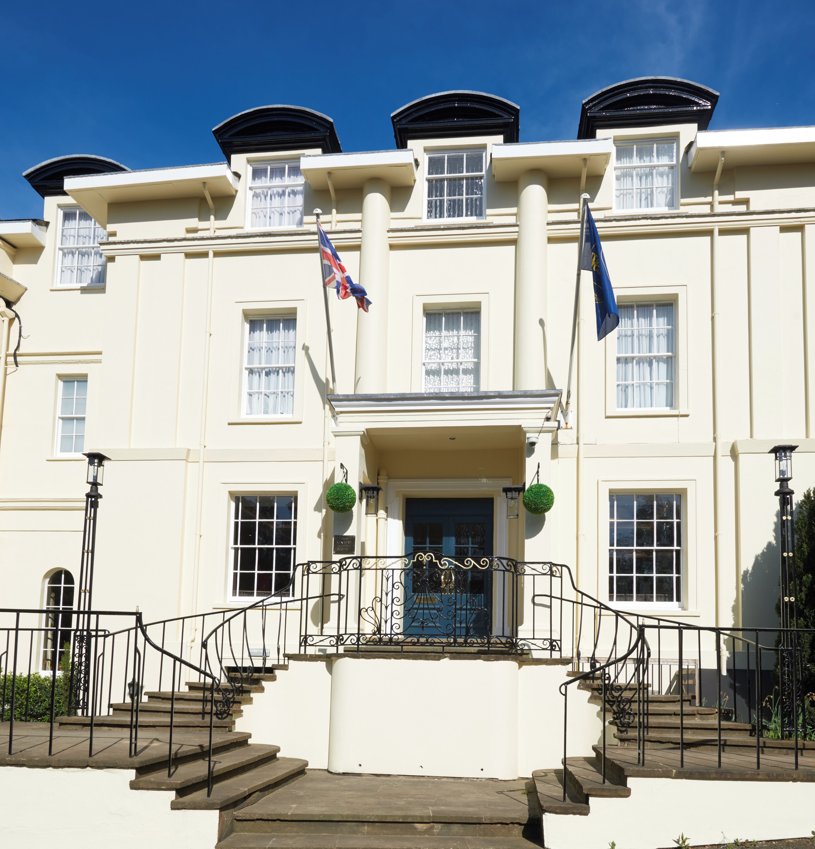 A building with a white facade, multiple windows, and a central entrance with a black wrought iron gate.