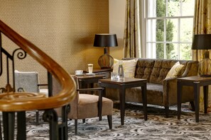 A cozy room with a patterned carpet, a sofa set, a coffee table, and a lamp.