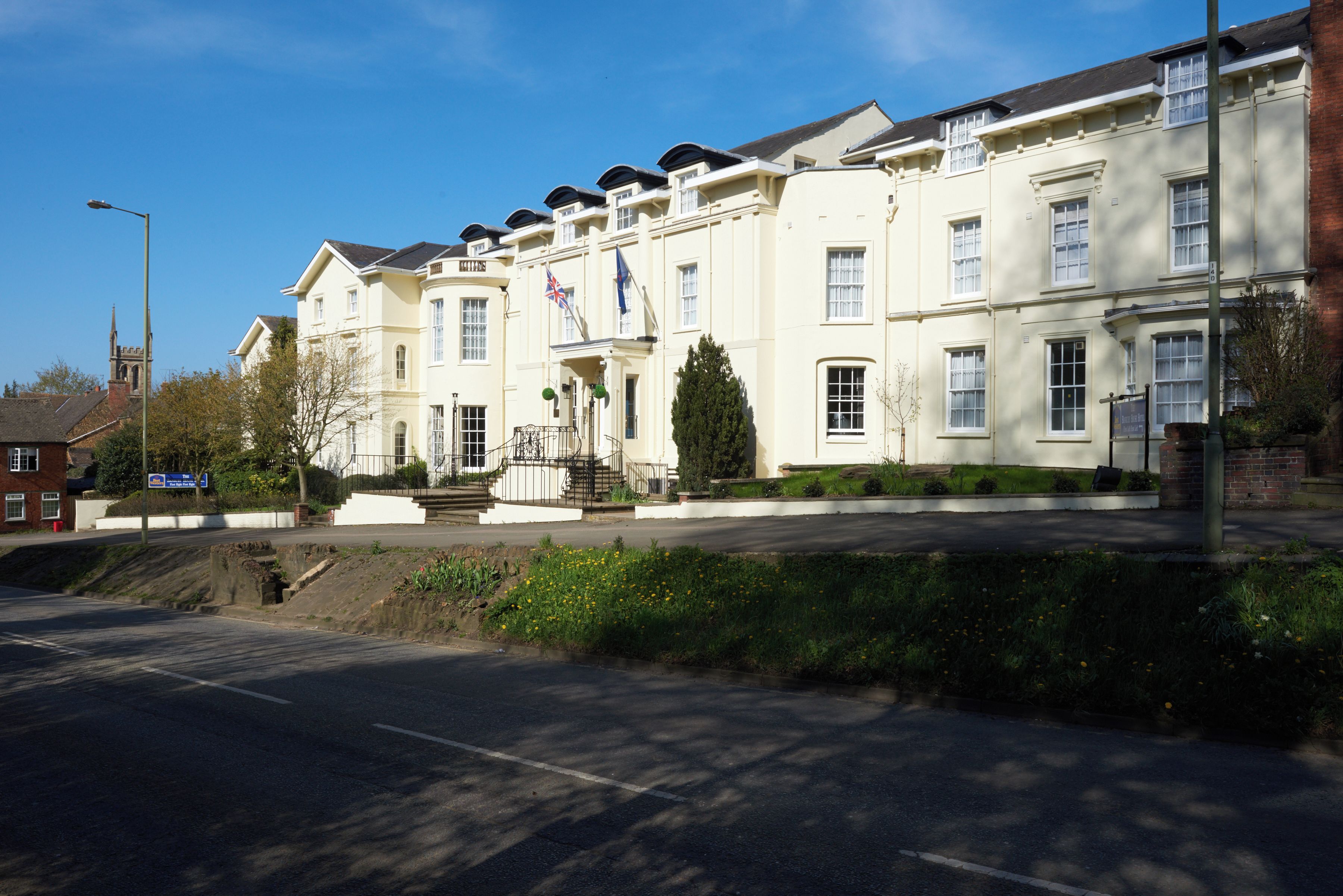 A multi-story building with a symmetrical facade, a central entrance with a staircase, and a flagpole.