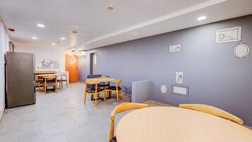 A modern kitchen with a refrigerator, stove, and dining area with chairs and a table.