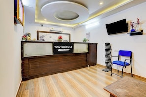 Un mostrador de recepción con un letrero que dice 'TOWNHOUSE Company-Serviced' y un televisor montado en la pared.