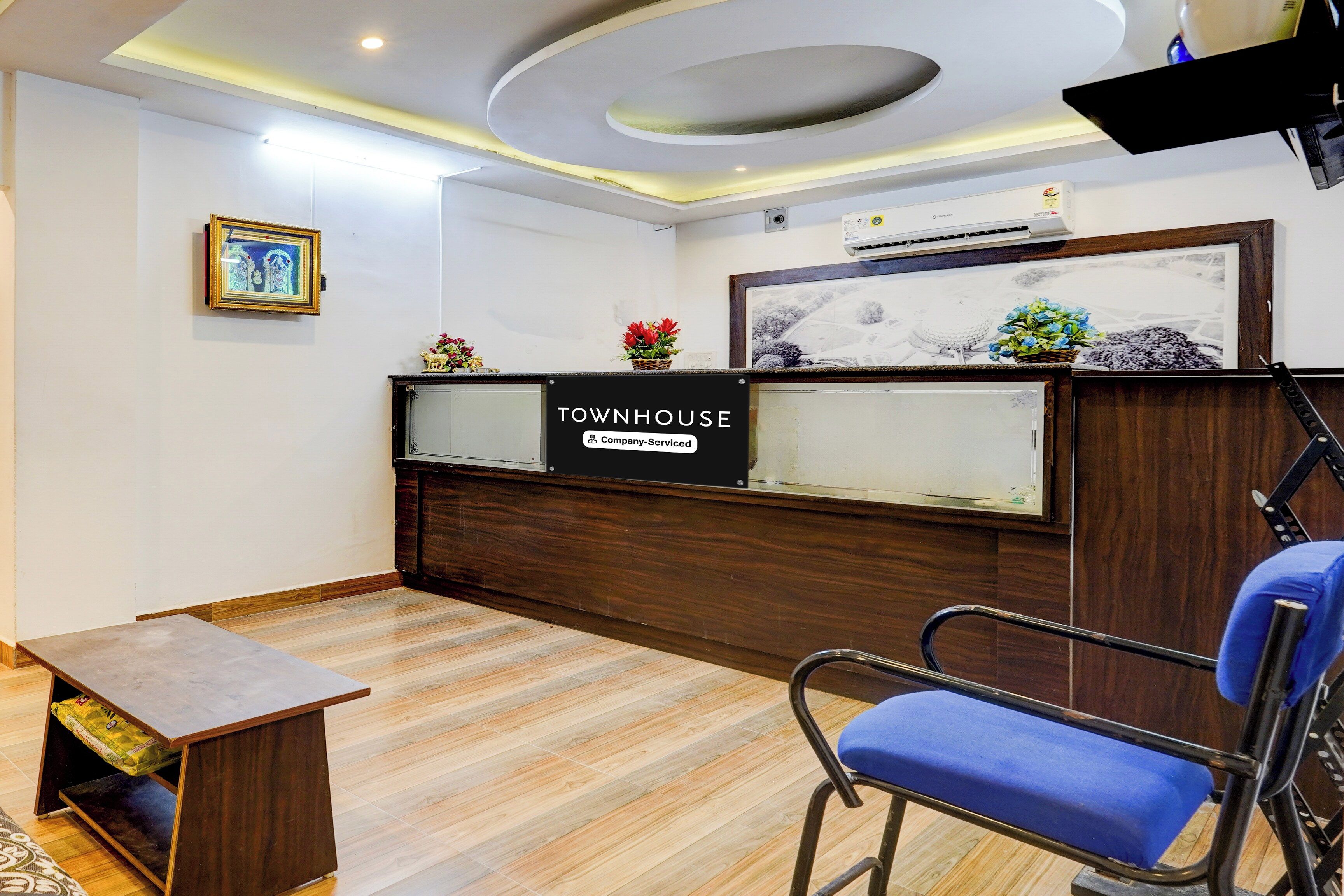 A reception area with a wooden reception desk, a blue chair, and a framed picture on the wall.