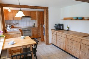 Una cocina con muebles de madera, una mesa de comedor con sillas y una cafetera.