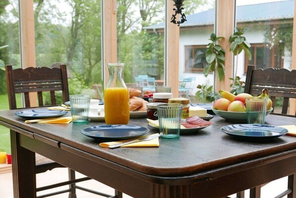 Ein Esszimmertisch mit Tellern, Gläsern, einer Orangensaftflasche und einer Obstschale.