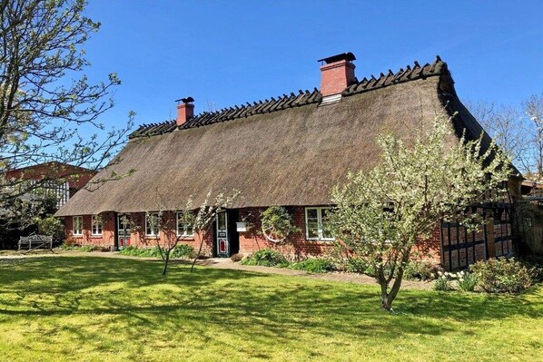 A traditional thatched-roof house with a brick exterior, a front door, and a small porch area. - Beautiful from fishing (Saustrup)
