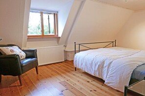 A bedroom with a bed, a chair, a radiator, and a window. - Beautiful from fishing (Saustrup)
