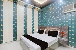 A hotel room with a bed, nightstand, and a wall-mounted air conditioner. - Hotel O Saryu Ghat (Ayodhya)