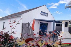 A modern white house with a sloped roof, a covered patio area, and a visible garage. - Holiday home in Zierow with swimming pool (Zierow)