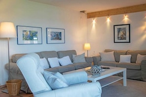 A living room with two grey sofas, a white armchair, a white coffee table, and three framed pictures on the wall. - Holiday apartment with 1 bedroom (Kappeln)