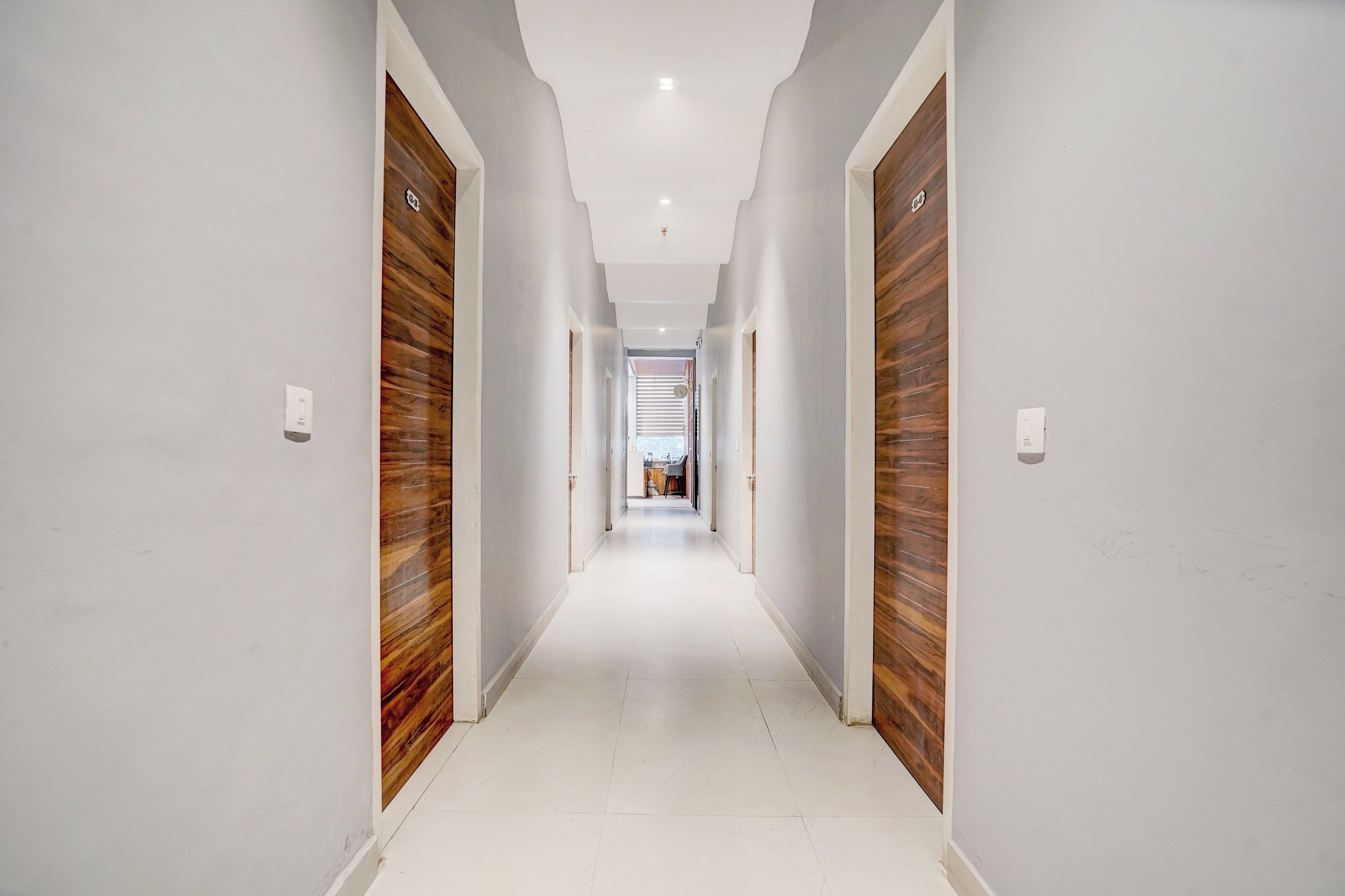 A long, narrow hallway with white walls and wooden doors on both sides.