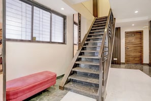 A staircase with a wooden finish, a red bench, and a door labeled '101'. - Collection O Crawford Market (Mumbai)