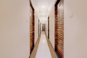 A hotel corridor with a central white carpet, flanked by wooden panel walls, and a ceiling with recessed lighting. - Collection O Crawford Market (Mumbai)