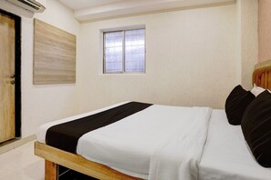 Un dormitori amb un llit individual, una finestra amb cortines, una porta de fusta i una paret amb relleu.