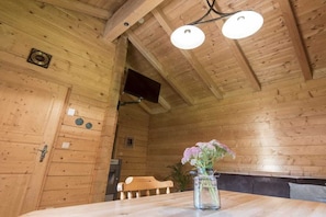 A wooden interior with a bench, a table with a vase of flowers, and a ceiling light fixture. - Holiday home in Rangersdorf with barbecue (Rangersdorf)