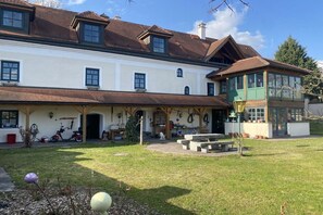 A two-story building with a covered porch, a separate green-roofed structure, and a well-maintained lawn. - Holiday apartment with 2 bedrooms (Emmersdorf)