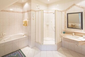 A bathroom with a bathtub, a glass-enclosed shower, and a vanity with a mirror.