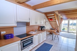 A kitchen with white cabinets, a wooden countertop, a built-in oven, and a dining area with a table and chairs. - Holiday apartment with 2 bedrooms (Kopperby)