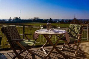 An outdoor seating area with a round table and two chairs, a bottle, and two wine glasses. - Holiday apartment with 2 bedrooms (Kopperby)