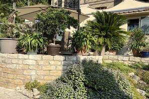 Un mur de pierre agrémenté de plantes en pot et d’un parasol de patio.
