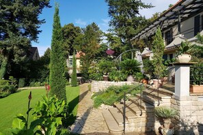 Une propriété résidentielle avec un chemin de pierre menant à un escalier, le tout entouré d’une végétation luxuriante et d’arbres.