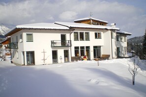 A two-story building with a balcony, large windows, and a snow-covered roof. - Holiday apartment in Söll with swimming pool (Söll)