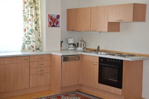 A kitchen with wooden cabinets, a dishwasher, a stove, and a coffee maker. - Holiday apartment in Söll with swimming pool (Söll)