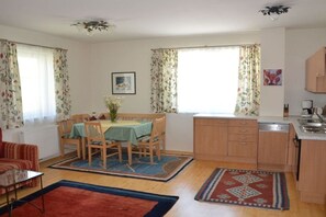 A compact living space with a dining area, kitchen, and a sofa. - Holiday apartment in Söll with swimming pool (Söll)