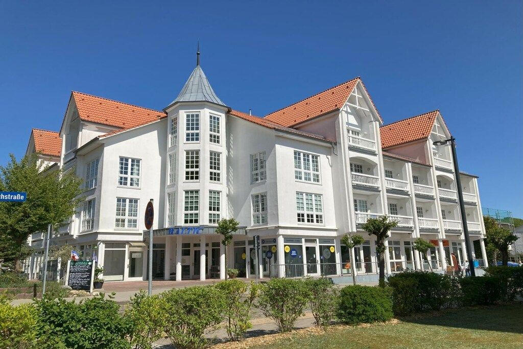 Een meerlaags hotel met een centrale toren, balkons en een dak van rode tegels.