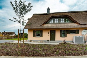 Ein Haus mit einem Strohdach, einer grünen Tür und einem kleinen Garten.