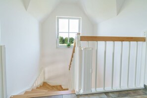 A staircase with a white railing, a window with a view of greenery, and a wooden handrail. - Holiday home with 1 bedroom (Boiensdorf OT Stove)