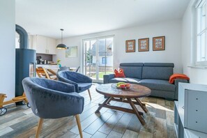 A modern living space with a sofa, chairs, a coffee table, and a kitchen area. - Holiday home with 1 bedroom (Boiensdorf OT Stove)