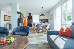 A modern living room with a fireplace, a dining area, and a kitchen. - Holiday home with 1 bedroom (Boiensdorf OT Stove)