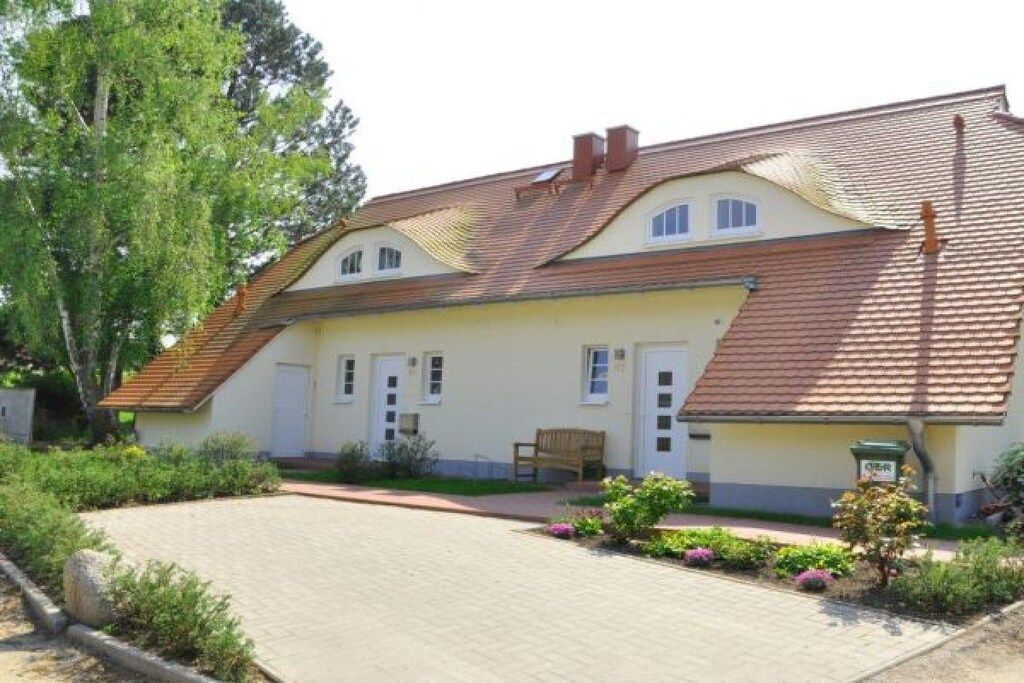 A two-story house with a tiled roof, a front porch, and a paved driveway.
