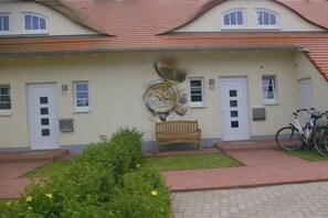 A building with a tiled roof, a wooden bench, and a bicycle parked outside. - Holiday home with 1 bedroom (Kaltenhof (Insel Poel))