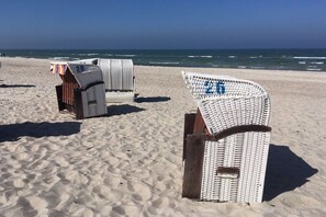 Sillas de playa con números, dispuestas sobre una playa arenosa con el océano al fondo.