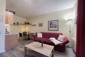 Espaço compacto com cozinha compacta, sofá vermelho, área de jantar e uma mesa.