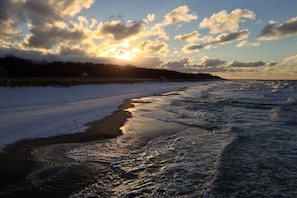 A beach with waves, a sunset, and a distant shoreline. - Holiday apartment with 1 bedroom (Dierhagen)