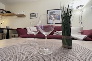 A room with a table set for two, a red sofa, a tall green plant, and a framed picture on the wall. - Holiday apartment with 1 bedroom (Dierhagen)
