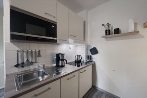 A modern kitchen with stainless steel appliances, a built-in microwave, and a coffee maker. - Holiday apartment with 1 bedroom (Dierhagen)