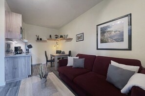 Un espacio habitable compacto con kitchenette, comedor y sofá.