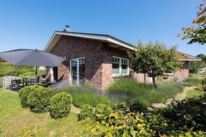 A brick house with a patio area, a table, and an umbrella. - Holiday home in Hohwacht with swimming pool (Hohwacht)