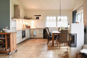 A kitchen with a dining area, a stove, a refrigerator, and a window with curtains. - Holiday home in Hohwacht with swimming pool (Hohwacht)