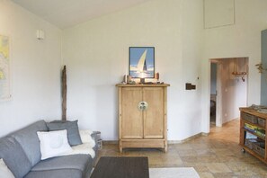A living room with a grey sofa, a wooden cabinet, and a framed picture on the wall. - Holiday home in Hohwacht with swimming pool (Hohwacht)