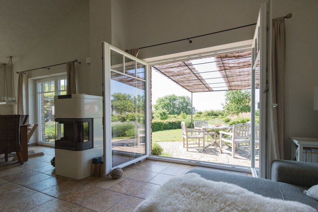 A room with a fireplace, a sofa, and a sliding glass door leading to an outdoor patio with a table and chairs.