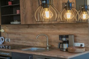 A kitchen with a wooden countertop, a stainless steel sink, a coffee maker, and a modern faucet. - Stubai farmhouse apartment (Telfes)